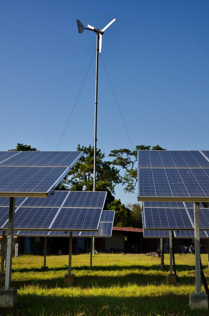 Solar panels and wind turbine against blue sky